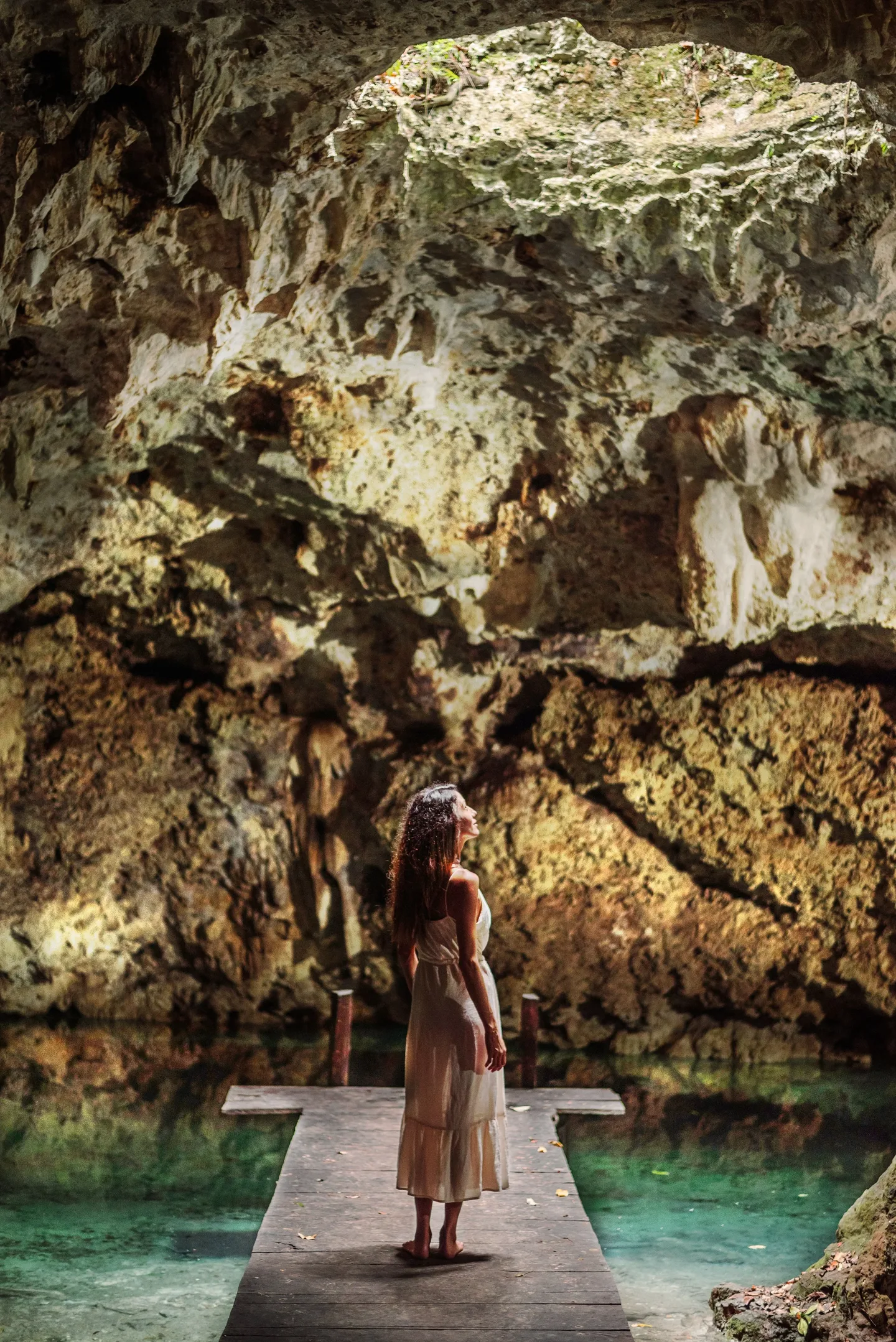 A woman on a wooden dock inside a cenote
