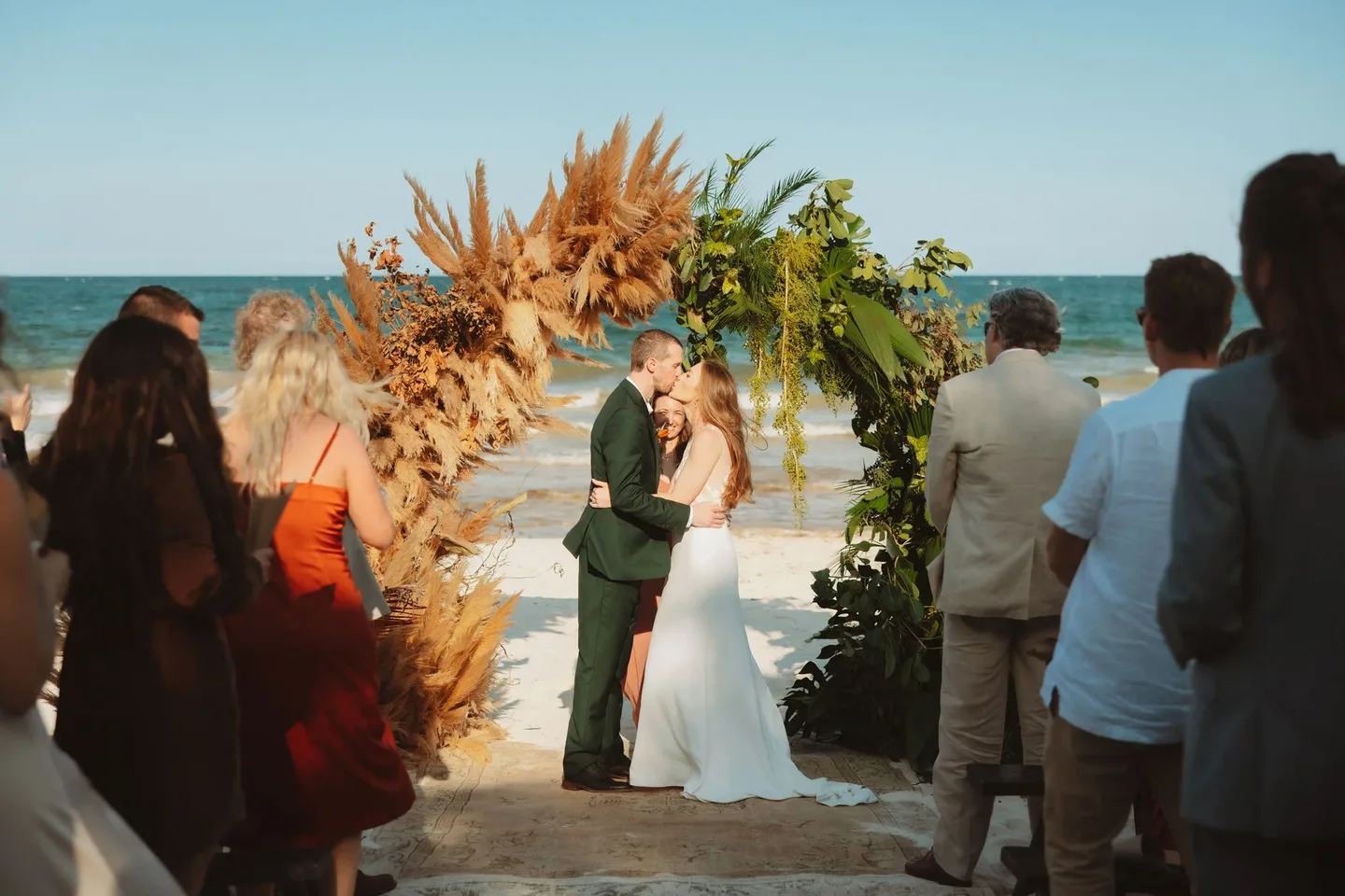 A couple kissing at a beach wedding ceremony