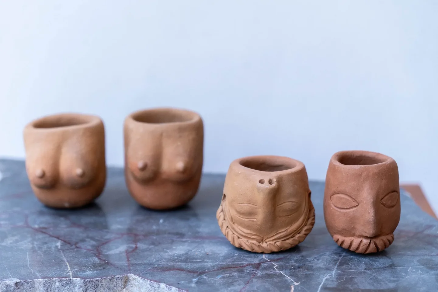 Four clay cups with face designs