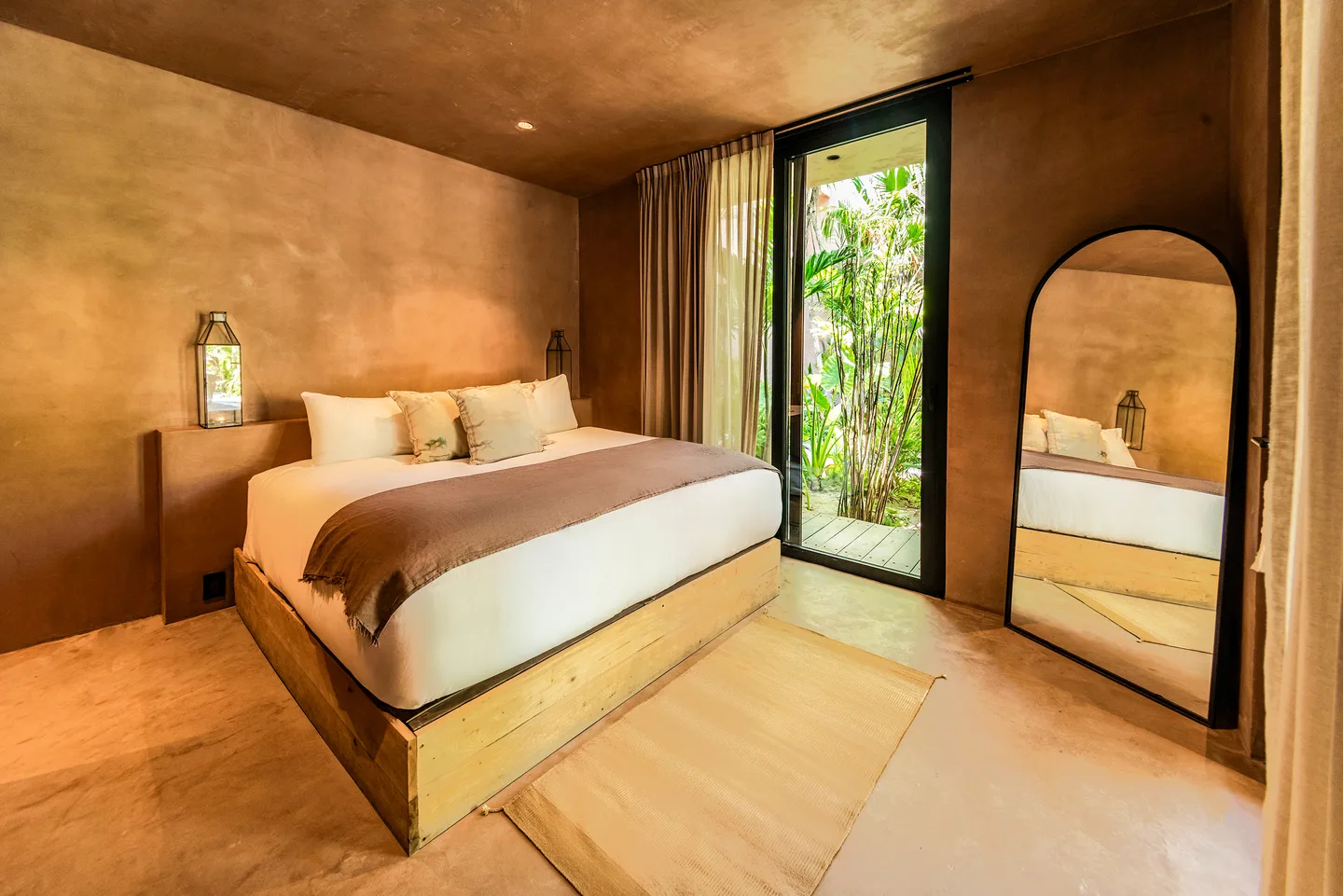 King bed with arched mirror beside the door to the garden