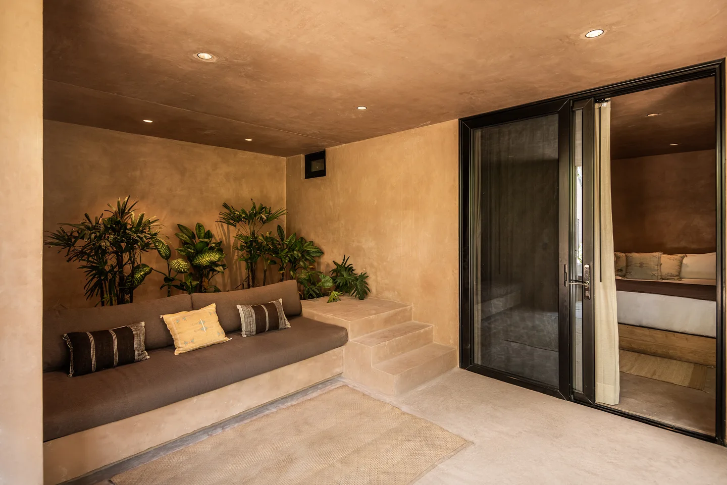 Patio interior con cama de día empotrada, plantas y escalones