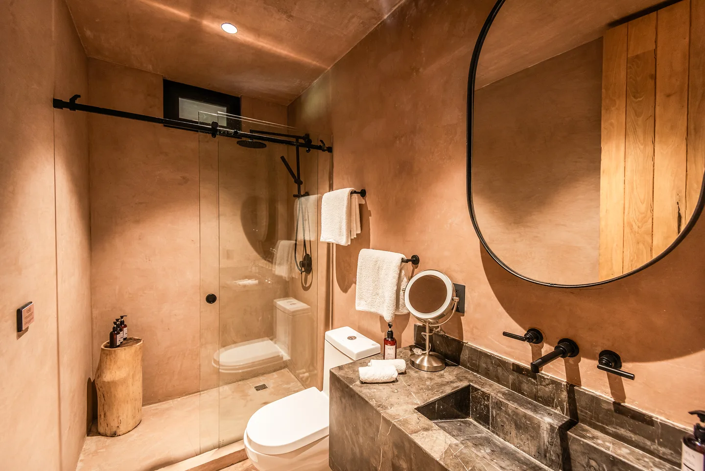 Baño con ducha de vidrio, lavabo de piedra y espejo ovalado