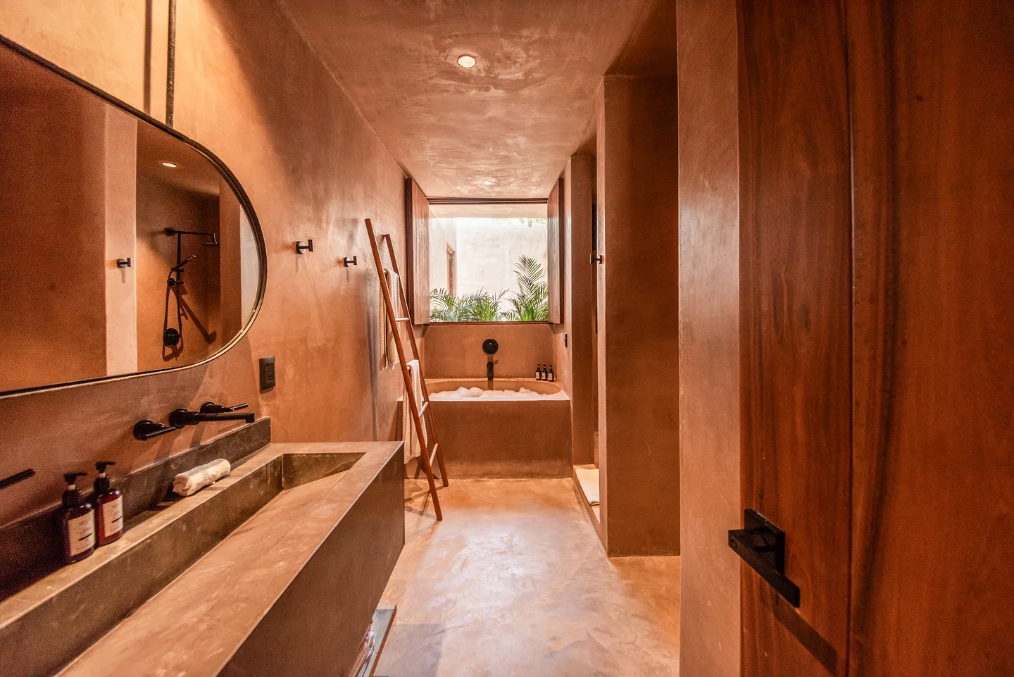 Baño con lavabo de piedra, espejo ovalado y bañera empotrada junto a la ventana