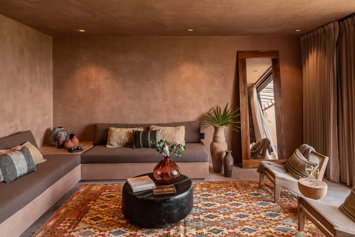 Sala de estar con sofá esquinero, mesa de centro redonda y tapete kilim