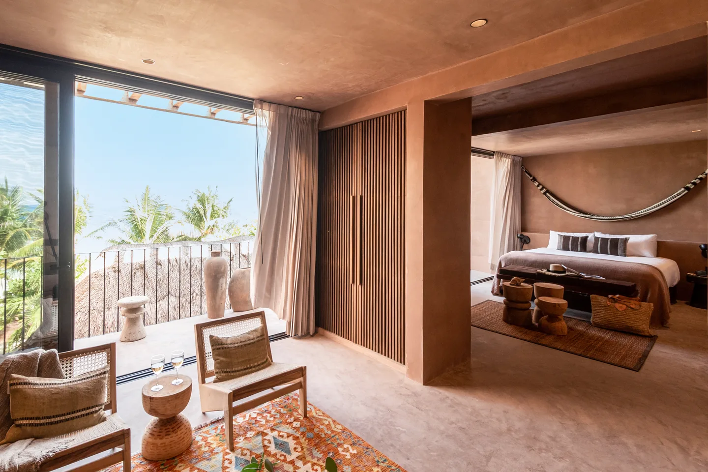 Suite opening onto its terrace, with the bed set in an alcove and palms beyond