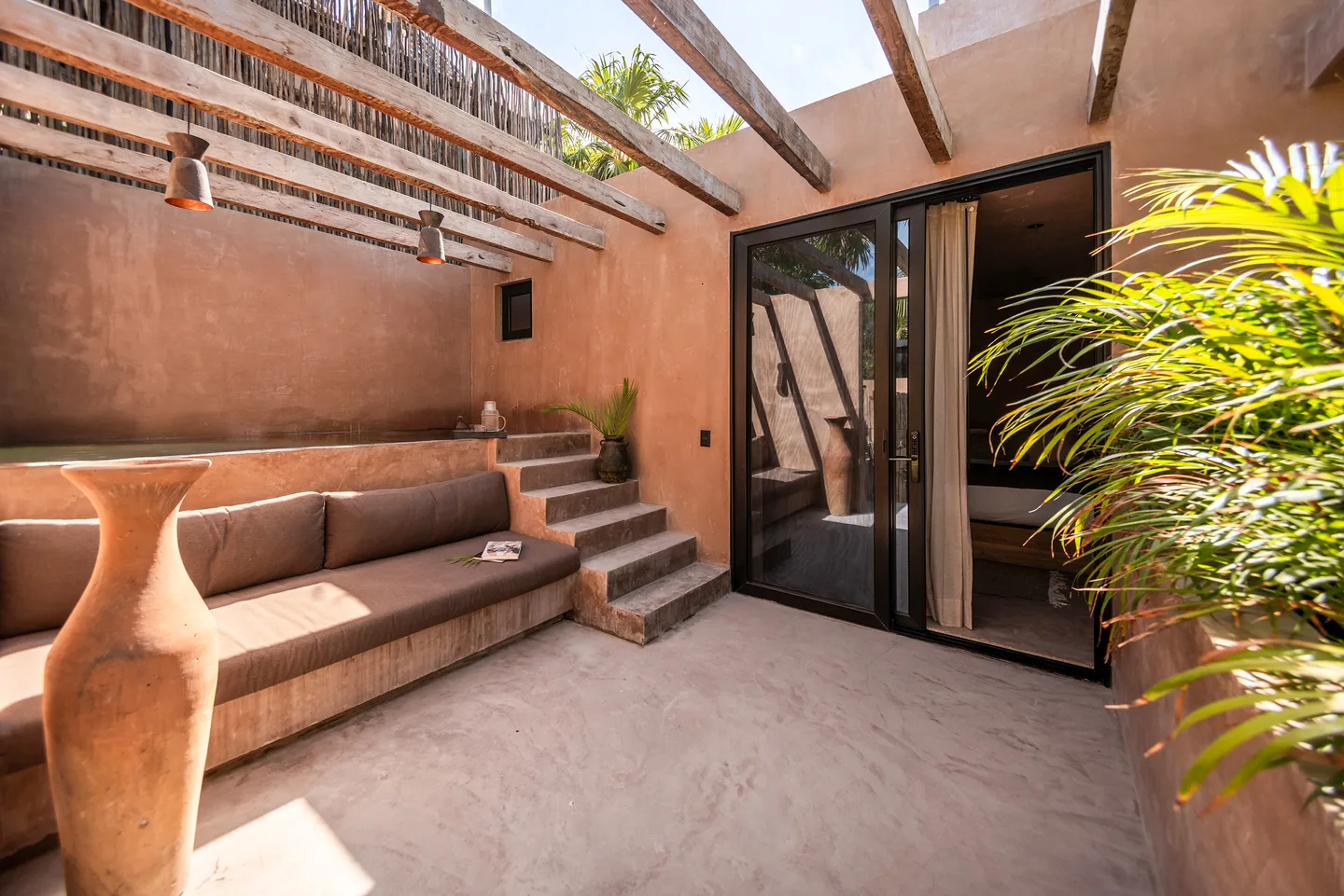 Patio privado con cama de día empotrada bajo una pérgola de madera
