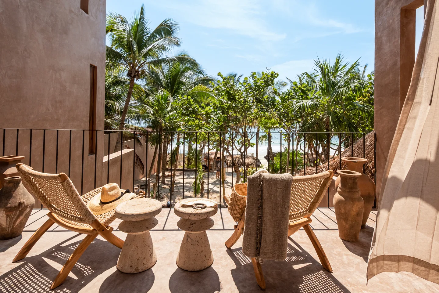 Terraza privada con sillas tejidas mirando hacia la playa entre las palmeras