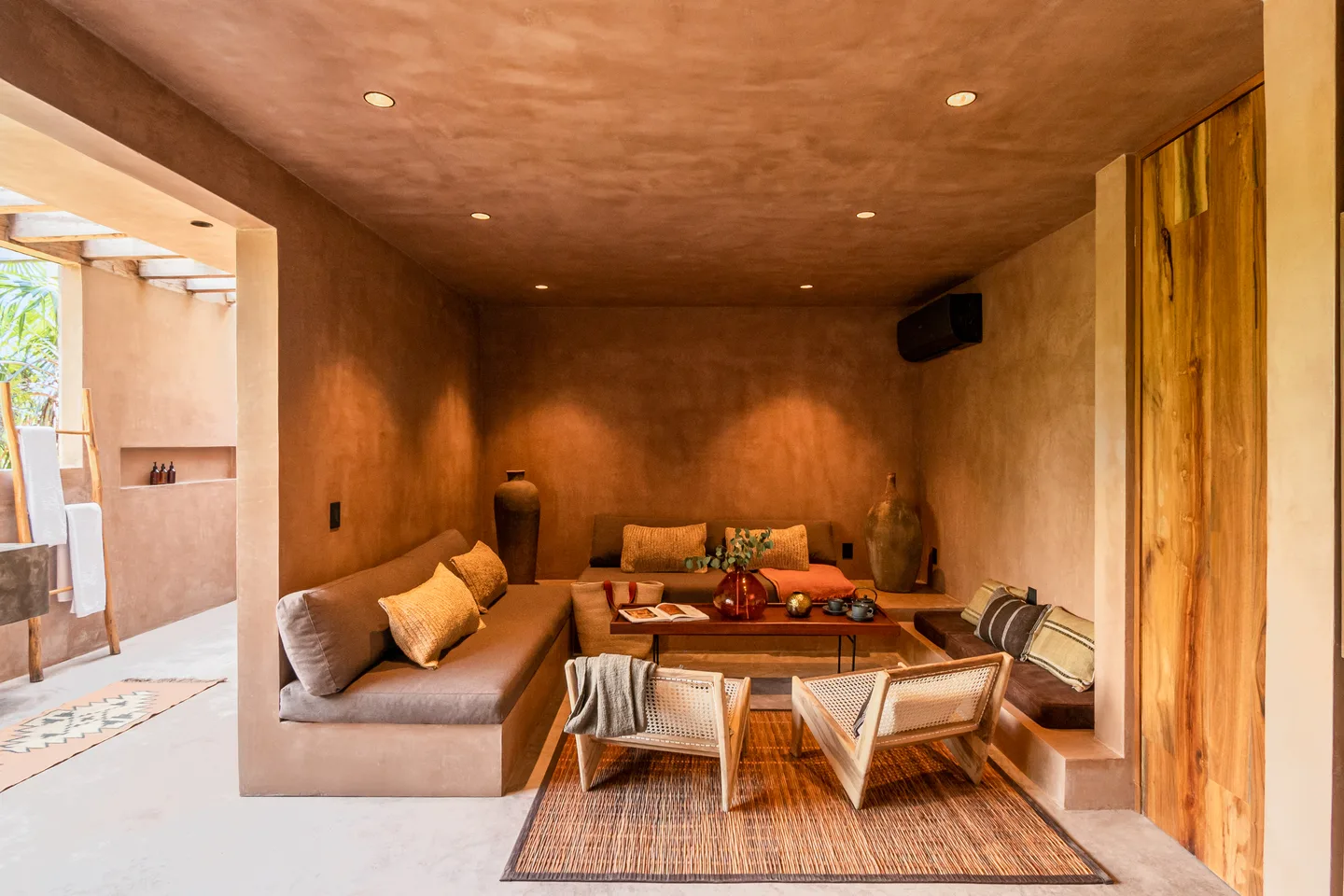 Sala de estar al aire libre con sofá integrado y sillones