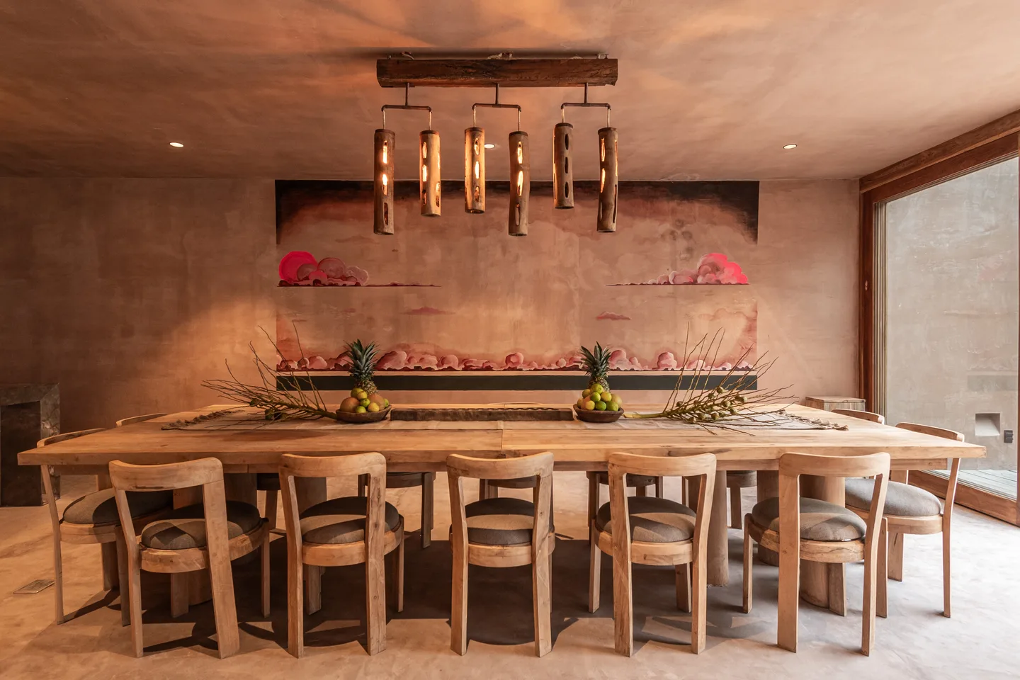Private dining room with a long wooden table for twelve beneath a hand-painted mural