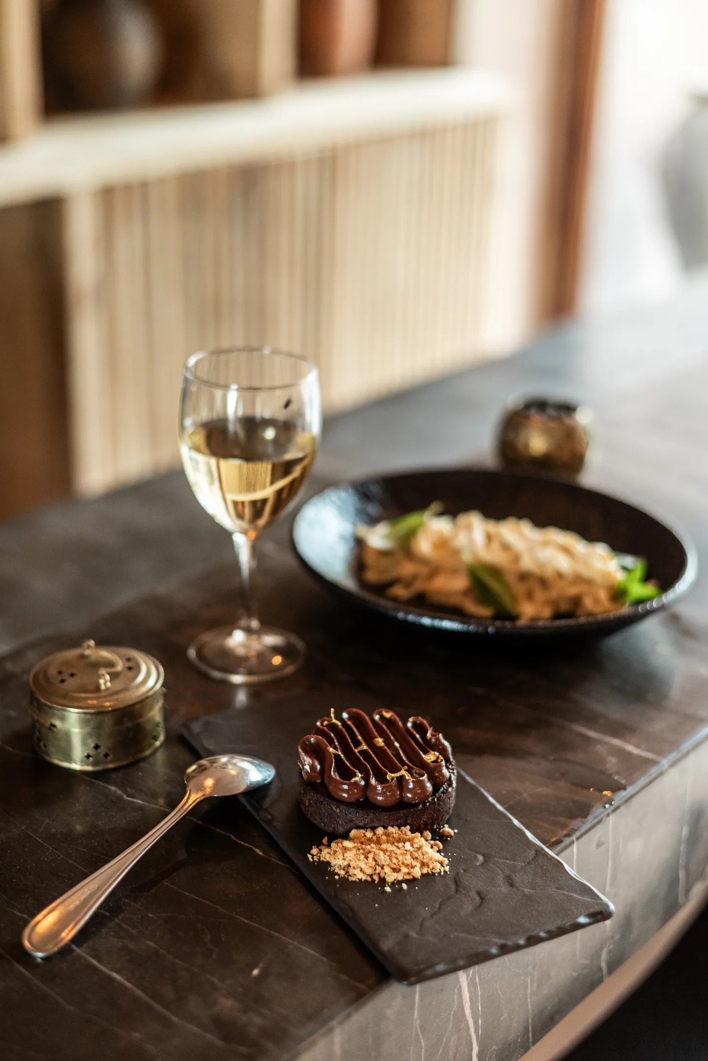 Noodle dish, dessert and a glass of white wine served on the stone bar