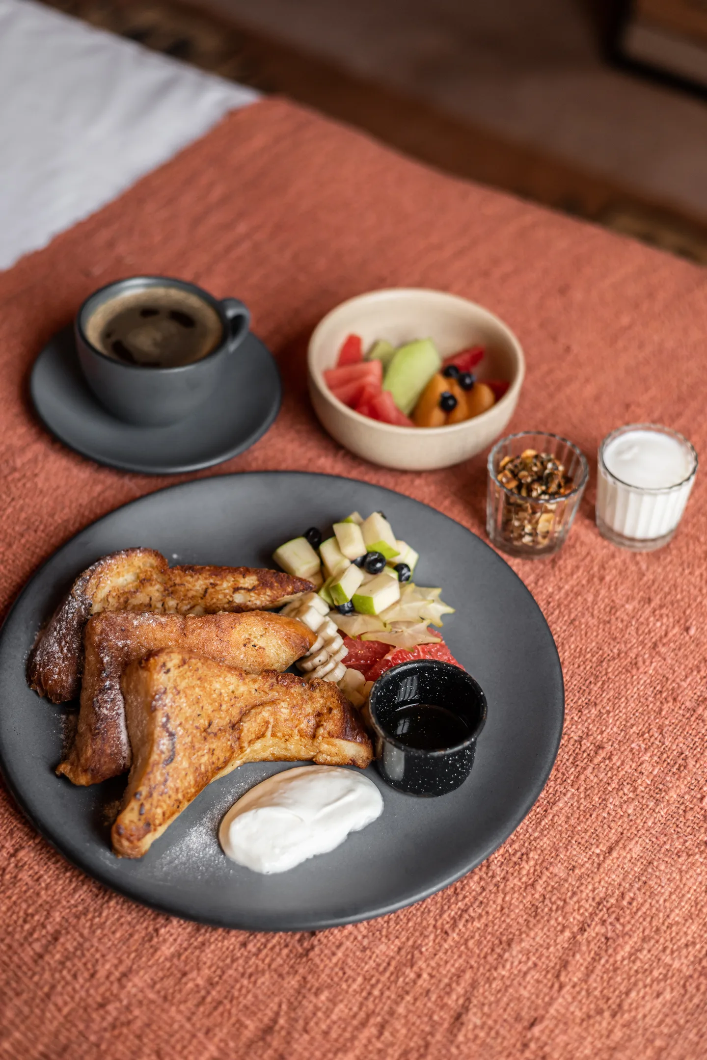 Breakfast of French toast, fruit and coffee served on a bed