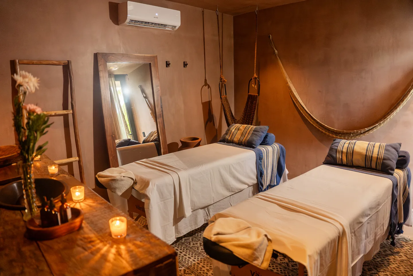 Spa cabin with two massage beds, candles and a woven hammock on the wall