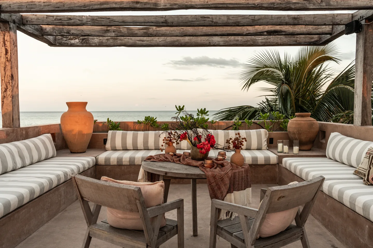 Rooftop lounge with striped banquettes and a table set for dinner overlooking the sea