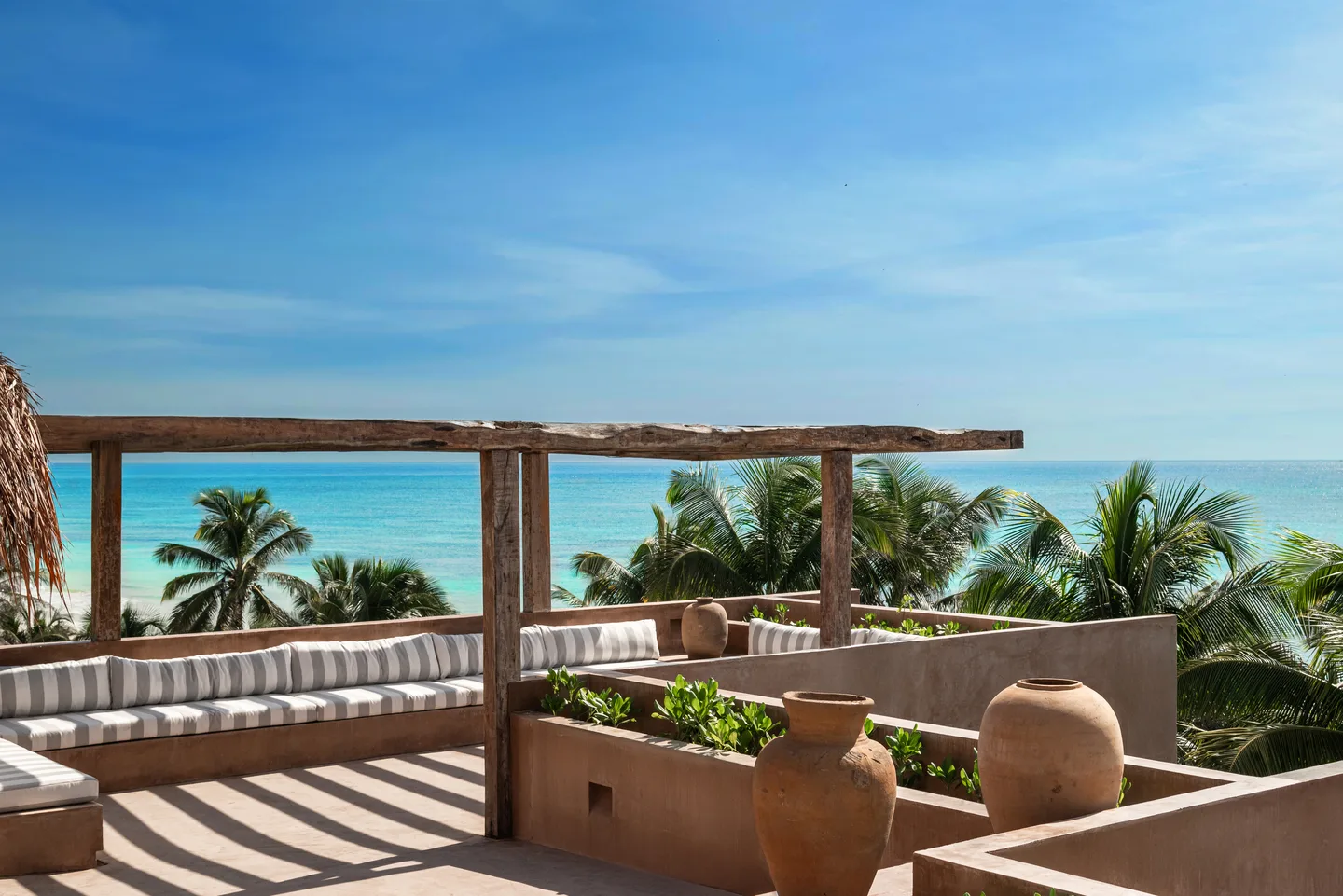 Rooftop terrace with pergola and clay urns above the palms and turquoise Caribbean