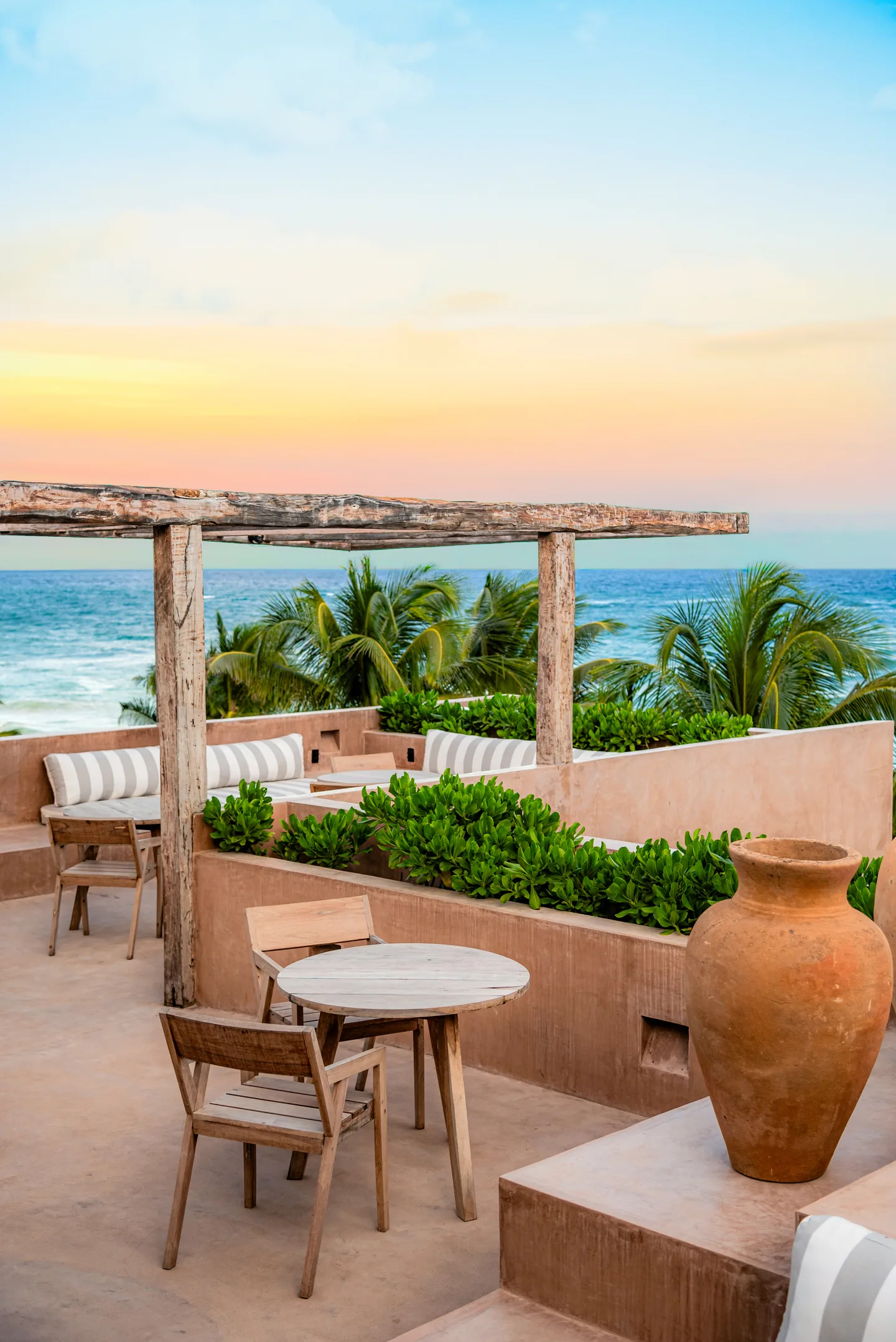 Rooftop terrace with cafe tables and pergola at sunset over the sea