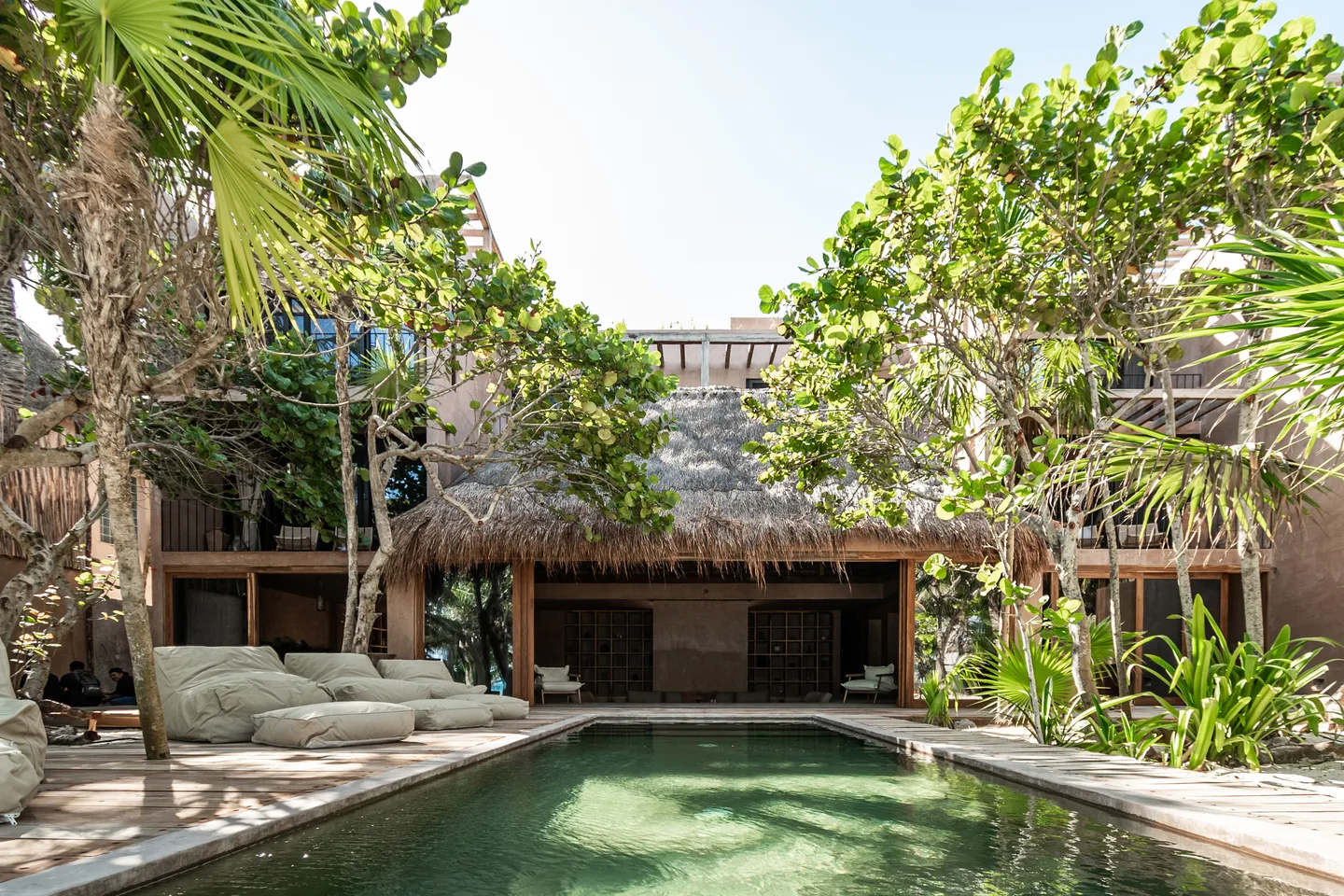 Pool and sun deck in front of the thatched palapa of the main house