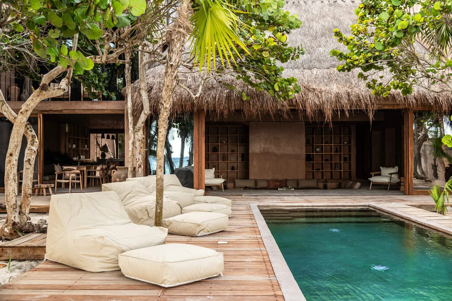 Pool deck with oversized loungers beside the thatched-roof lounge
