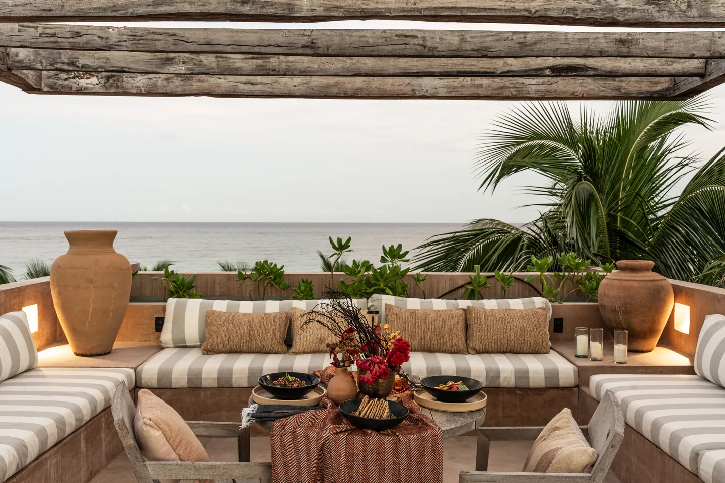 Private rooftop dinner table dressed with flowers and candles facing the sea