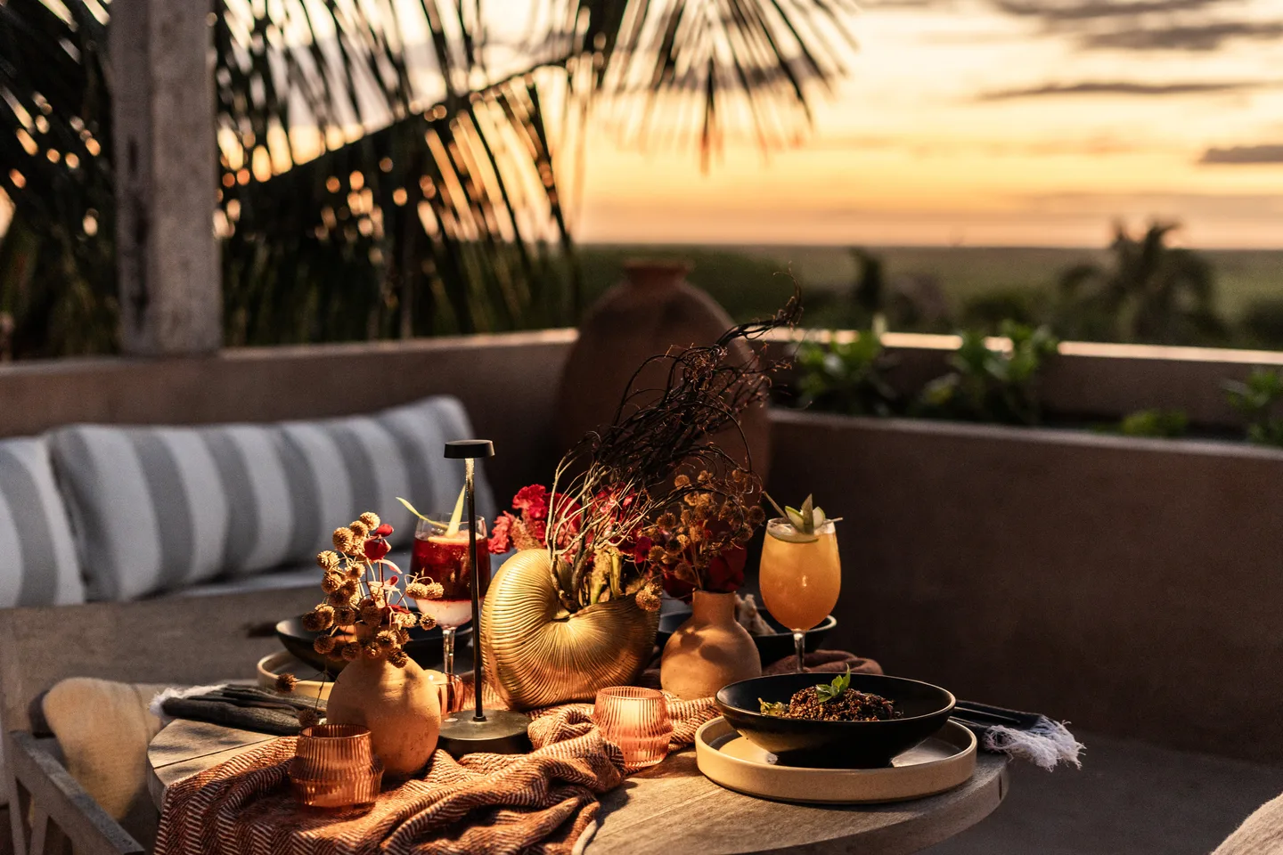 Private dinner table with flowers, candles and cocktails at sunset
