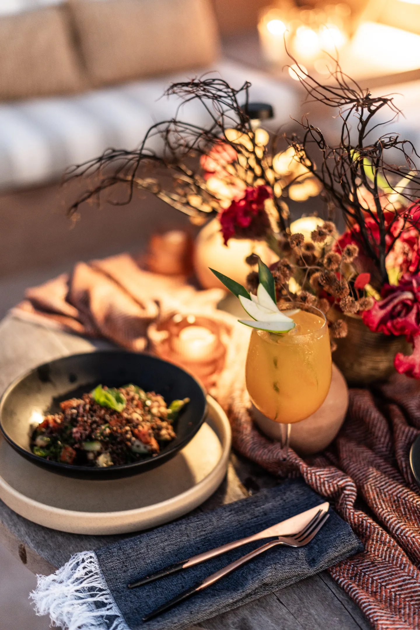 Plated dish and a cocktail on a table dressed with dried flowers