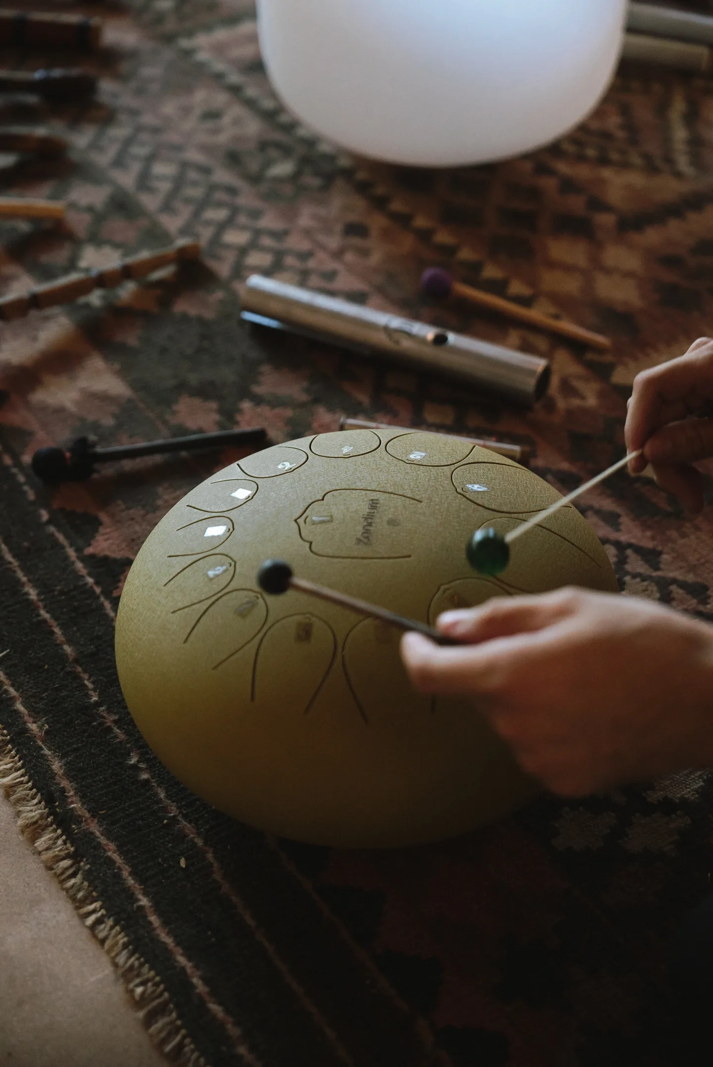 Hands playing a steel tongue drum during a sound healing session