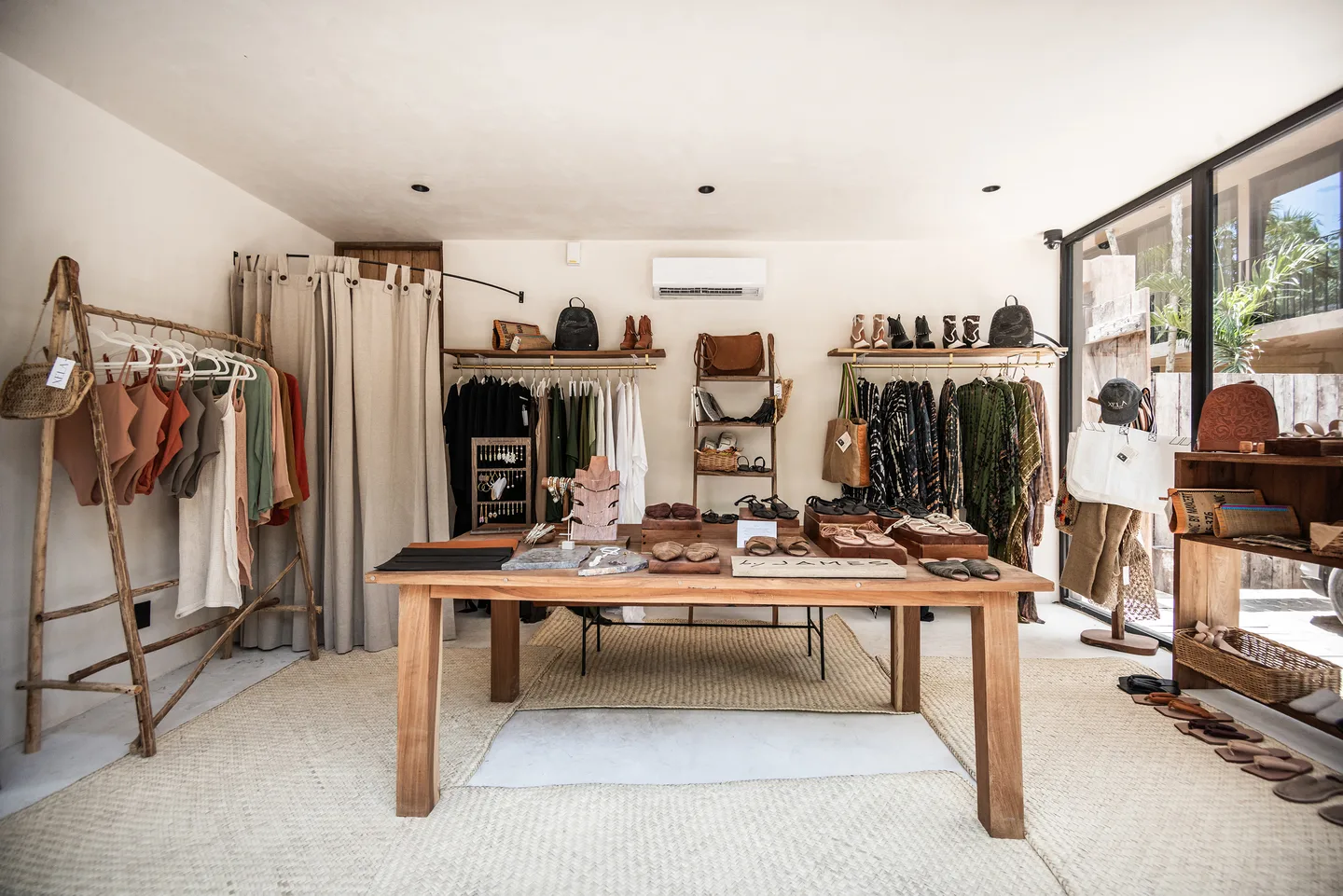 Boutique interior with clothing rails, leather goods and a wooden display table