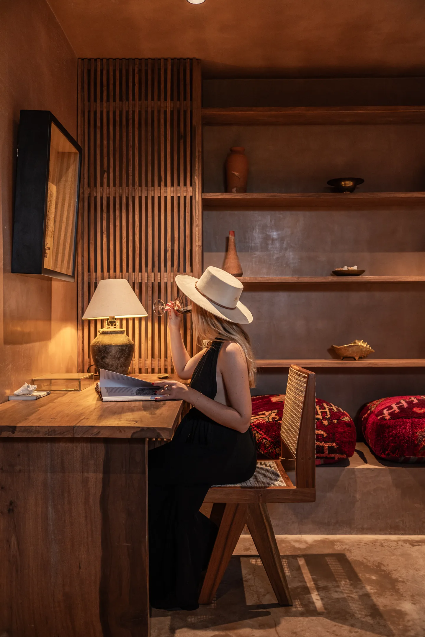 Guest writing at a wooden desk by lamplight in a suite