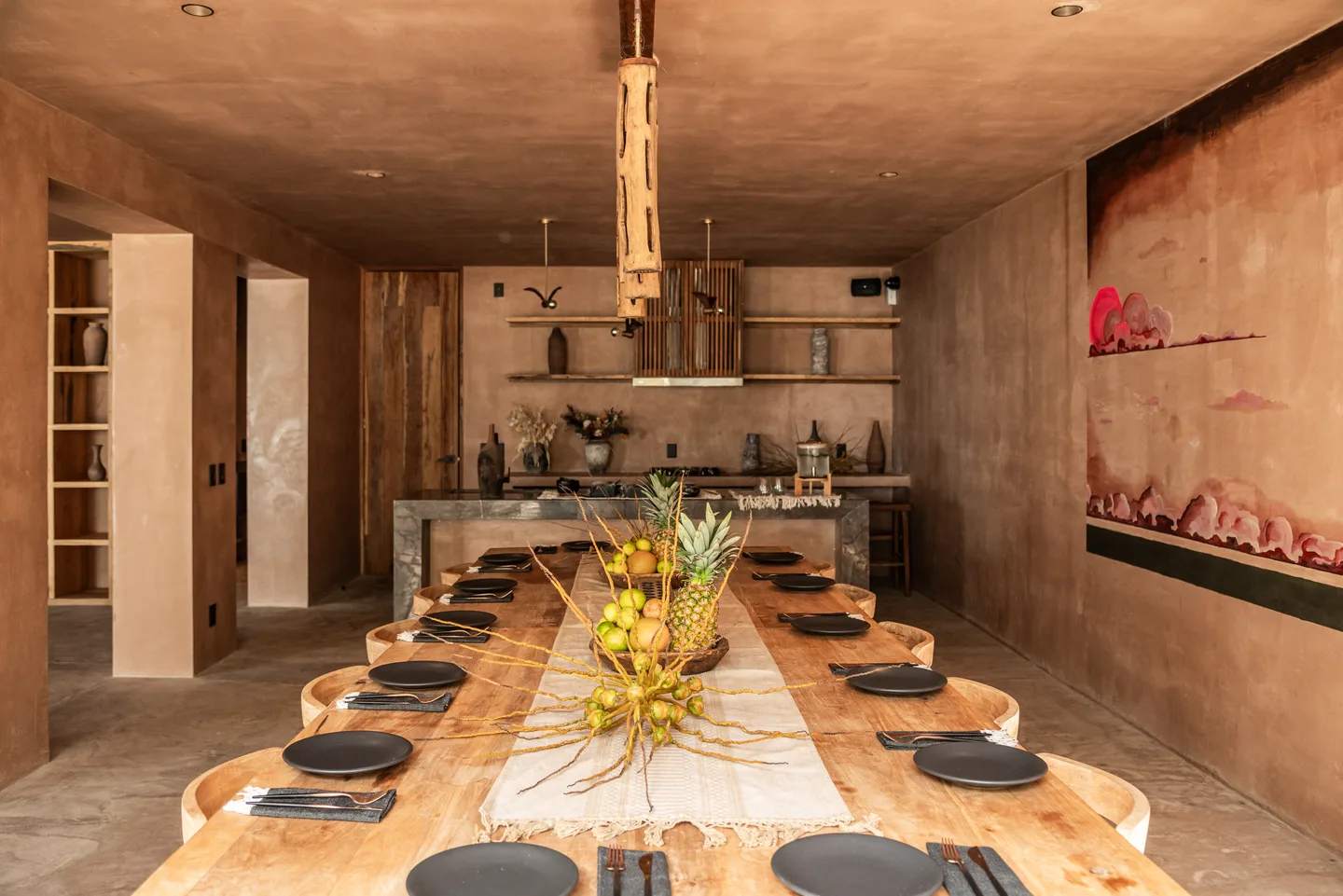 Long wooden table set for a private dinner in front of the open kitchen