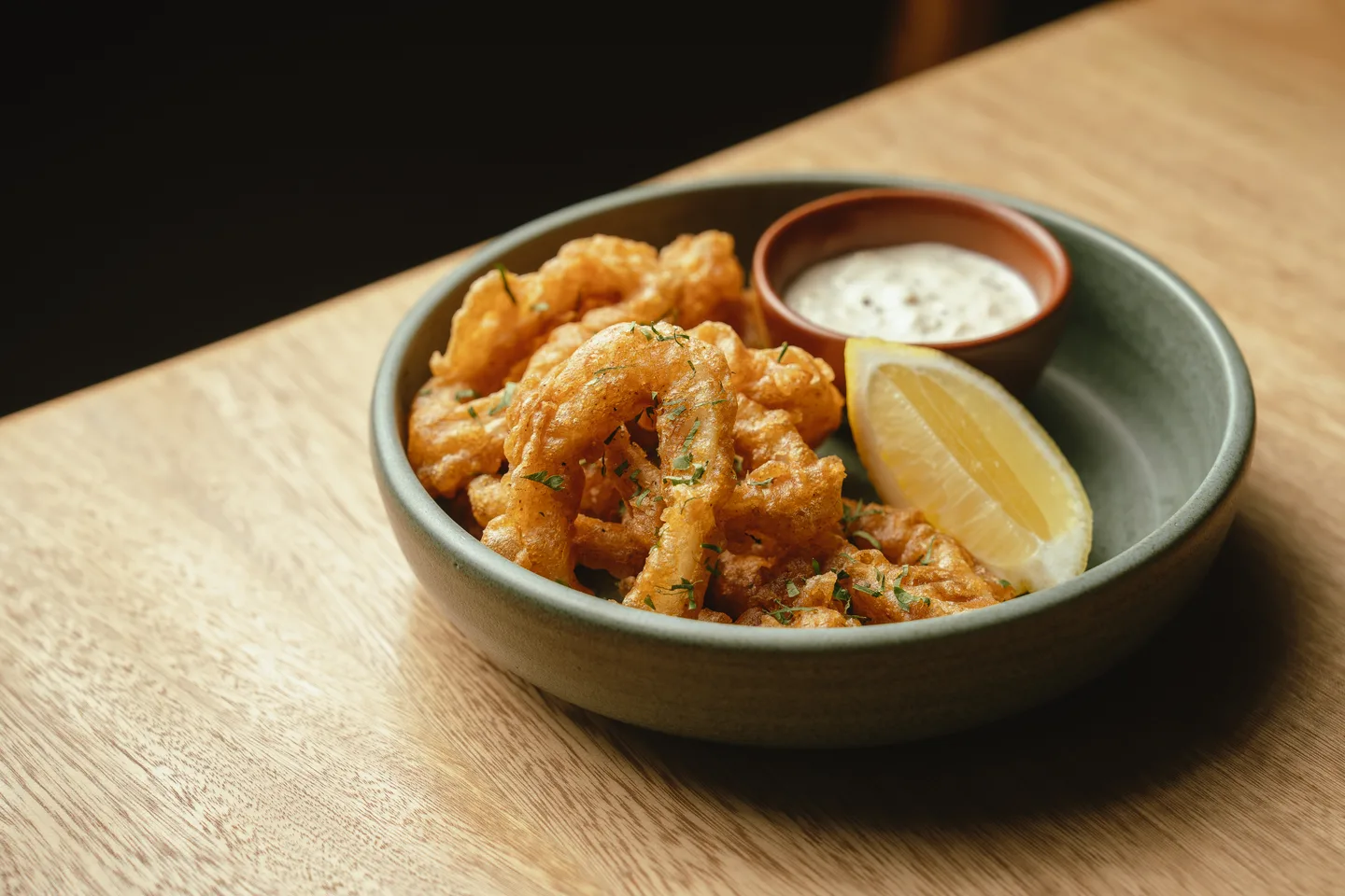 Fried calamari with lemon and tartar sauce in a ceramic bowl