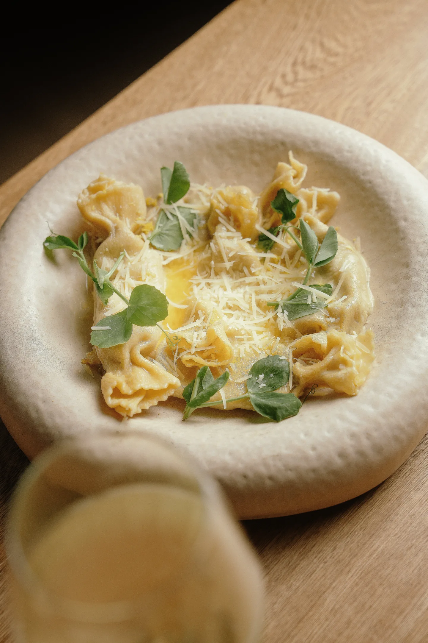 Ravioli with grated cheese and fresh herbs in a stoneware bowl