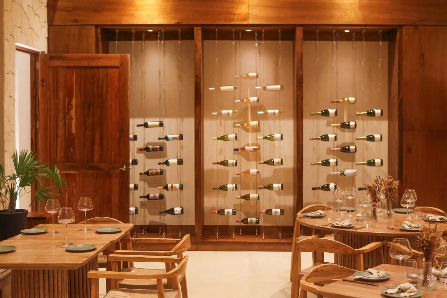 Climo dining room with a suspended wine display wall framed in dark wood