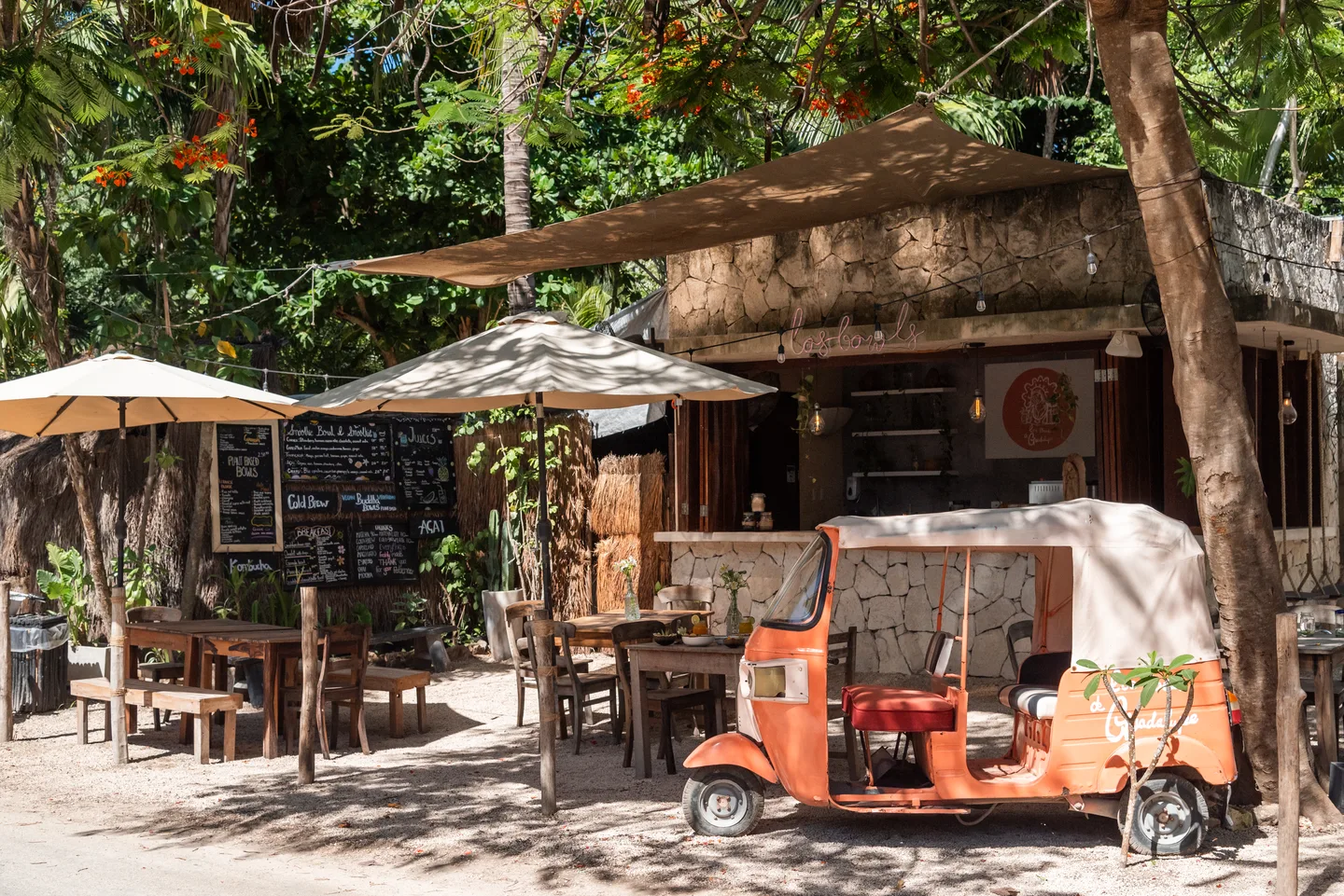 Los Bowls de Guadalupe roadside shack with shaded tables, chalkboard menus and an orange tuk-tuk