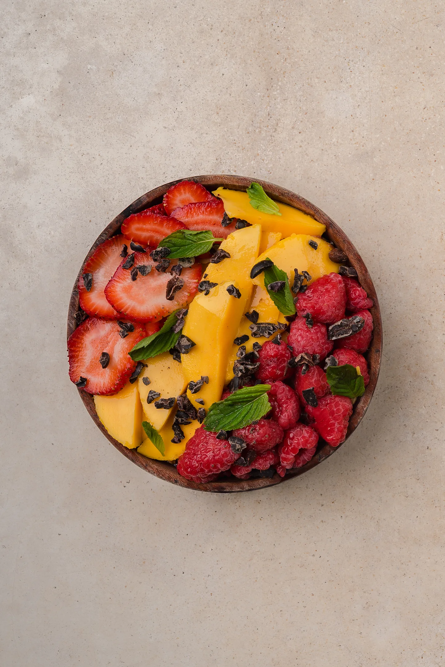 Fruit bowl of strawberries, mango and raspberries in a wooden bowl
