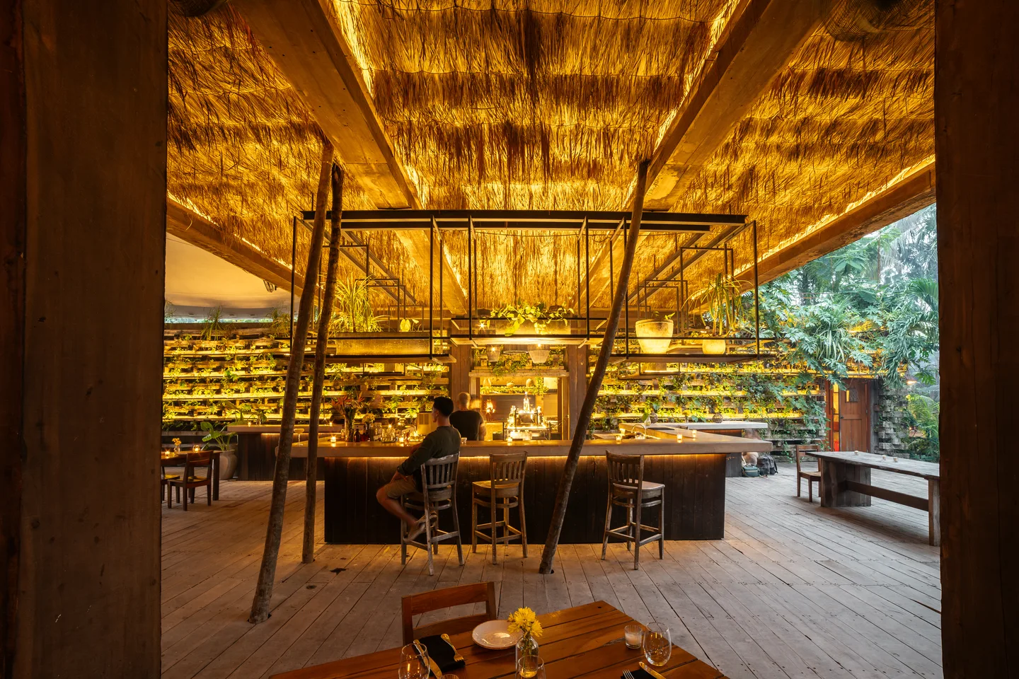 NÜ Tulum open-air dining room and bar glowing under a thatched roof in the jungle