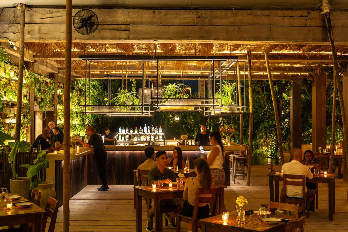 Guests dining by candlelight around the central bar at NÜ Tulum