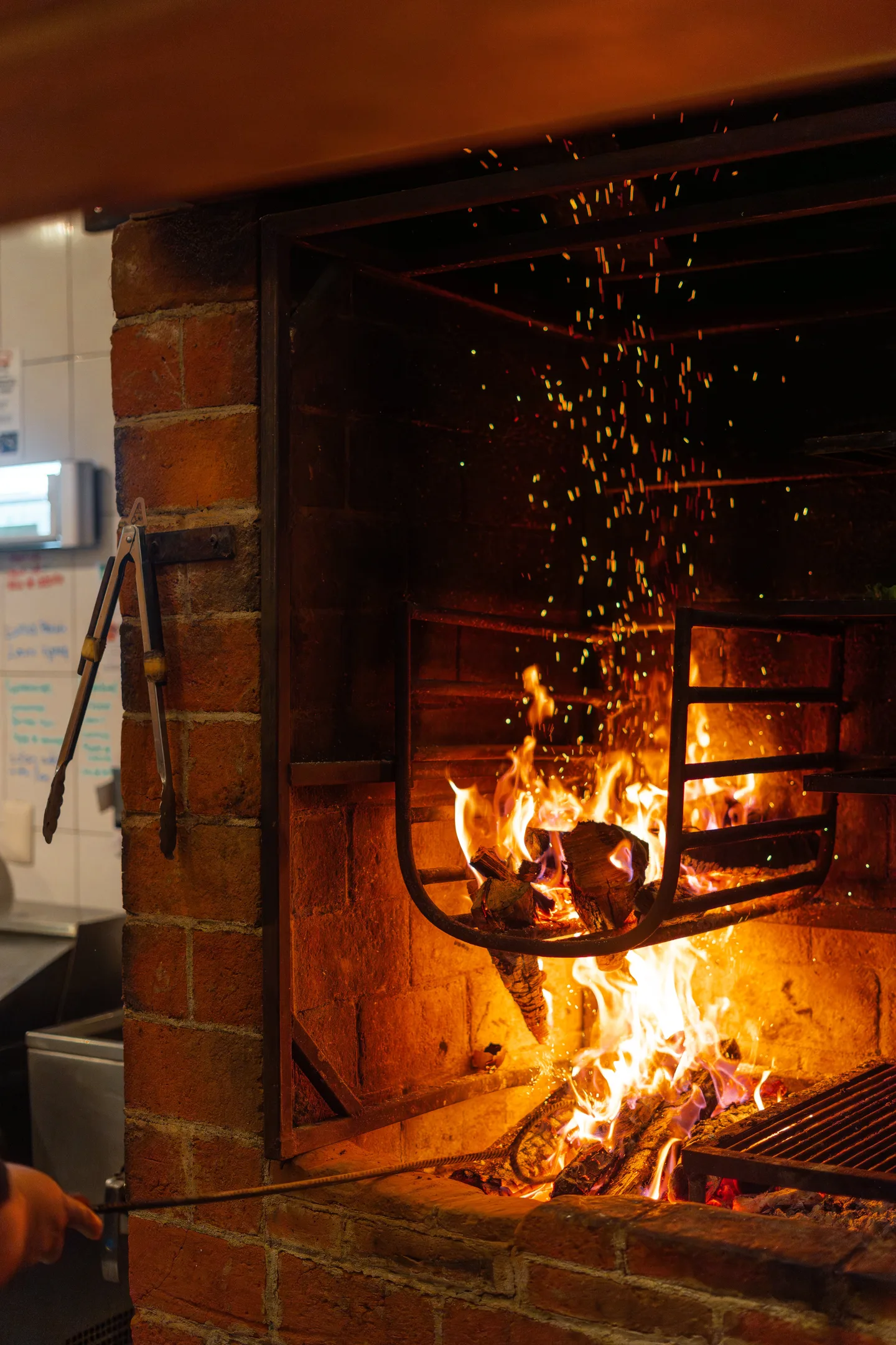 Wood fire burning in the brick grill of the NÜ Tulum kitchen
