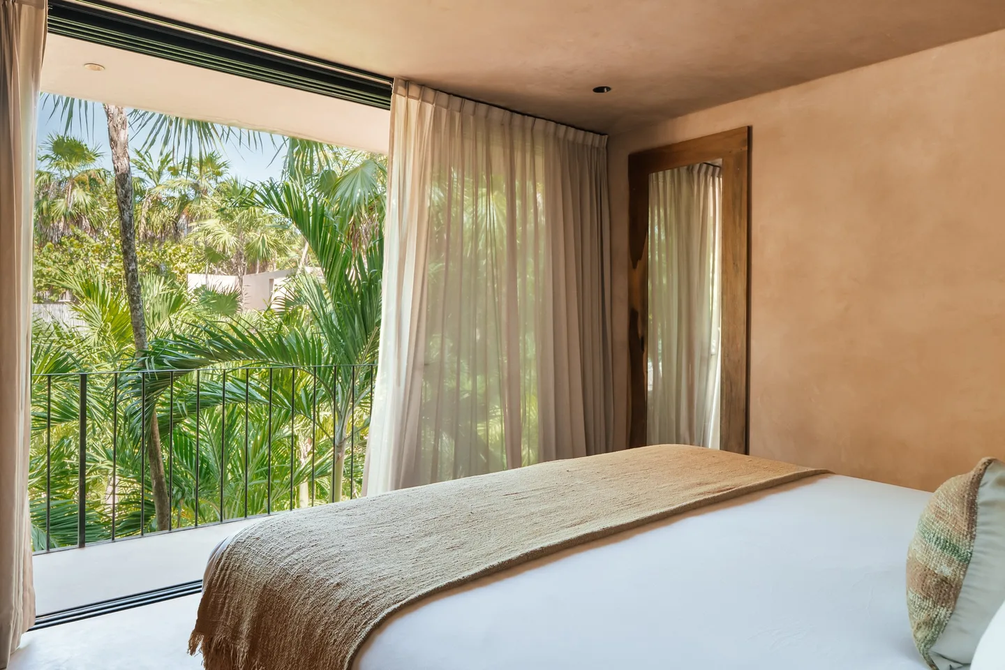 Bed facing floor-to-ceiling windows and a balcony over the jungle